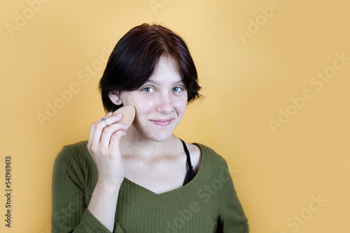 Skin care concept, teenage girl wants to have darker skin and applies toner cream on her face and smiles, teenage girl has clear healthy facial skin photo