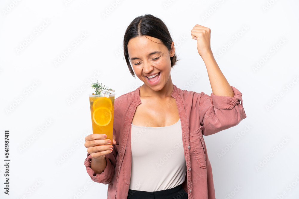 Young hispanic woman holding a cocktail isolated on white background celebrating a victory Young hispanic woman holding a cocktail isolated on white background celebrating a victory