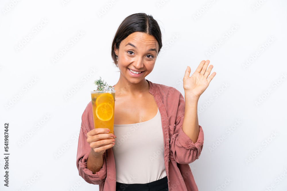 Young hispanic woman holding a cocktail isolated on white background saluting with hand with happy expression Young hispanic woman holding a cocktail isolated on white background saluting with hand with happy expression