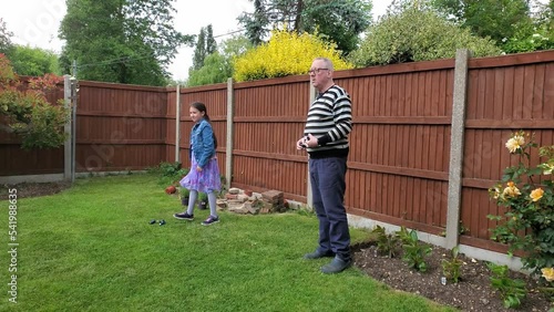 Caucasian Granddaughter and Grandfather playing in backyard garden a game of petanque, Colchester, Essex