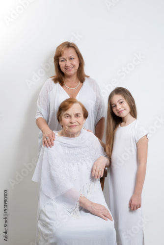 Portrait of women of the same family of different generations and ages in light clothes on a white background.