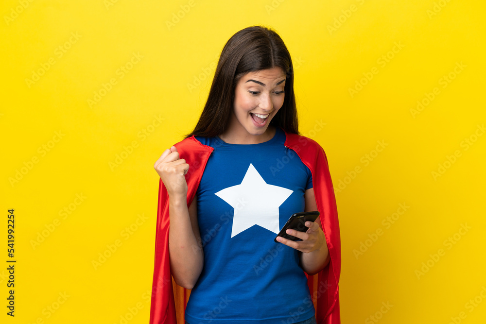 Super Hero Brazilian woman isolated on yellow background surprised and sending a message Super Hero Brazilian woman isolated on yellow background surprised and sending a message