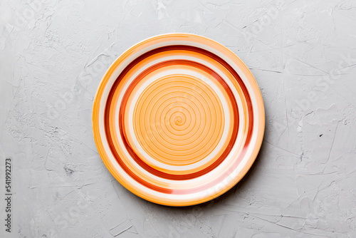 Top view of empty orange plate on cement background. Empty space for your design