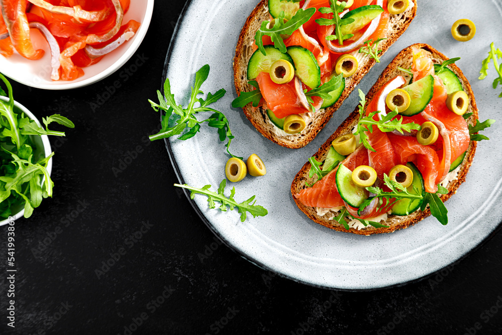 Toasts with salted salmon, arugula, green olives and cucumber. Top view Toasts with salted salmon, arugula, green olives and cucumber. Top view