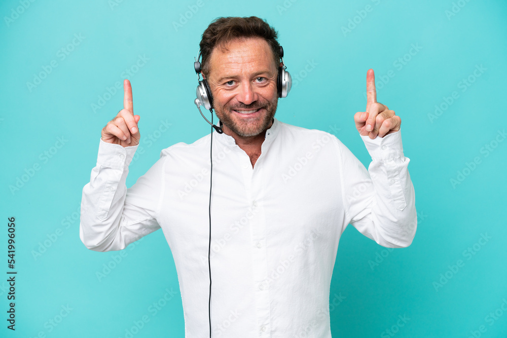 Telemarketer caucasian man working with a headset isolated on blue background pointing up a great idea Telemarketer caucasian man working with a headset isolated on blue background pointing up a great idea