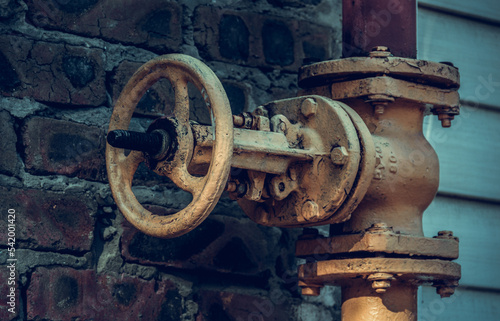 Old gas pipe valve. Yellow gas pipe on brick wall background. City communications