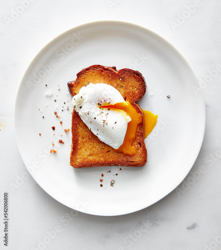 Poached egg on toasted bread on white plate with crumbs photo