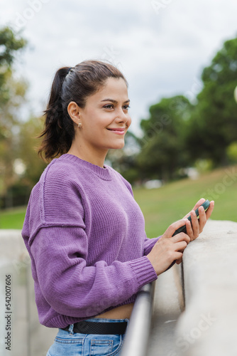 beautiful woman in purple blouse smiling outdoors with a cell phone in her hands