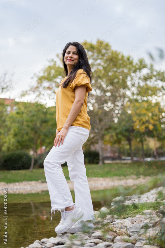 pretty girl in the park wearing yellow posing with a small lake in the background pretty girl in the park wearing yellow posing with a small lake in the background