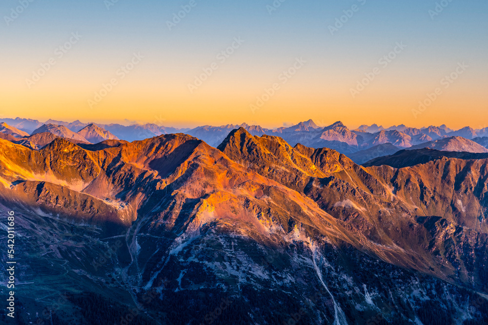 Naklejka premium Alpine mountain peaks illuminated by rising sun