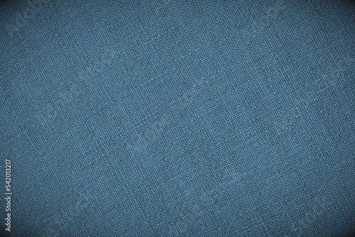 Blue woven surface close-up. Linen textile texture. Fabric sewing background. Textured braided backdrop with wignetting. Len wallpaper. Macro