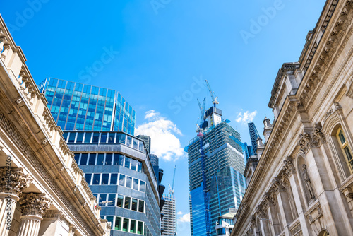 Looking up low angle view on Threadneedle street between stock Royal Exchange and Bank of England central institution buildings in City of London UK