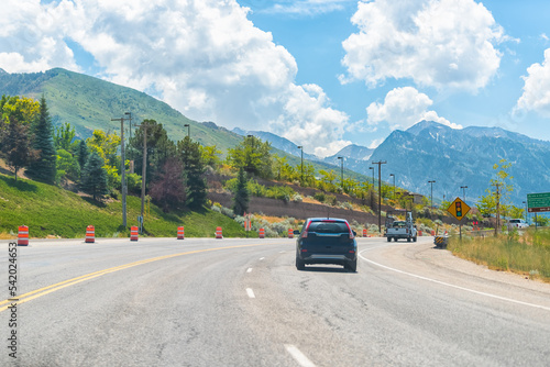 Cars driving on interstate highway road at Park City, Utah ski resort town with Wasatch mountains in summer background photo
