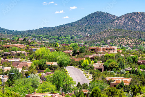 Cityscape of Santa Fe, New Mexico city by Sangre de Cristo mountains and road street by adobe traditional houses luxury wealthy community photo