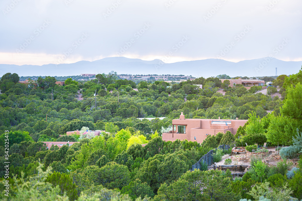 Cityscape view in Santa Fe, New Mexico Sangre de Cristo mountains by residential street community, green plants in summer and adobe traditional houses