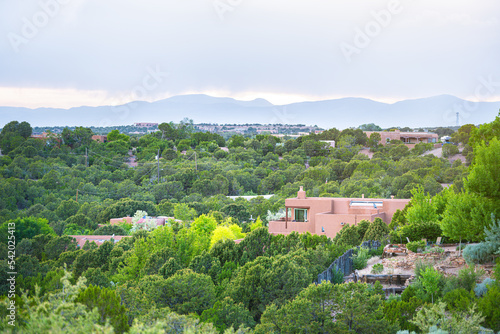 Cityscape view in Santa Fe, New Mexico Sangre de Cristo mountains by residential street community, green plants in summer and adobe traditional houses photo
