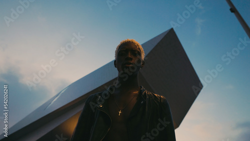 Portrait Of Black Guy In Night. Background Of Modern Building.