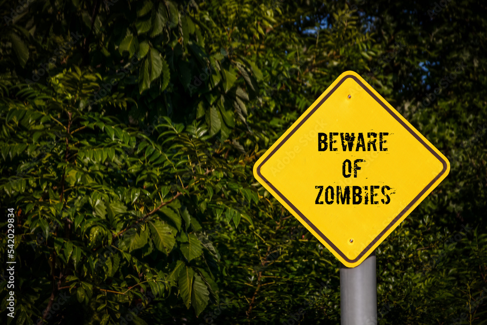 Yellow Caution Sign reading Beware of Zombies with Dark foliage background - Halloween