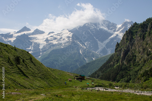 Pastoral mountain landscape with peaks with glaciers and a bright alpine meadow with green grass in a valley near Elbrus in the North Caucasus