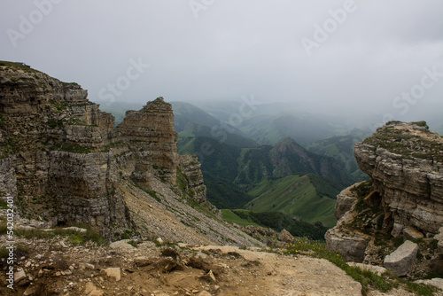 Sharp rocks on the Bermamyt mountain plateau on a cloudy summer day and a hazy haze blurred on the horizon and a space for copying in Karachay-Cherkessia in the North Caucasus