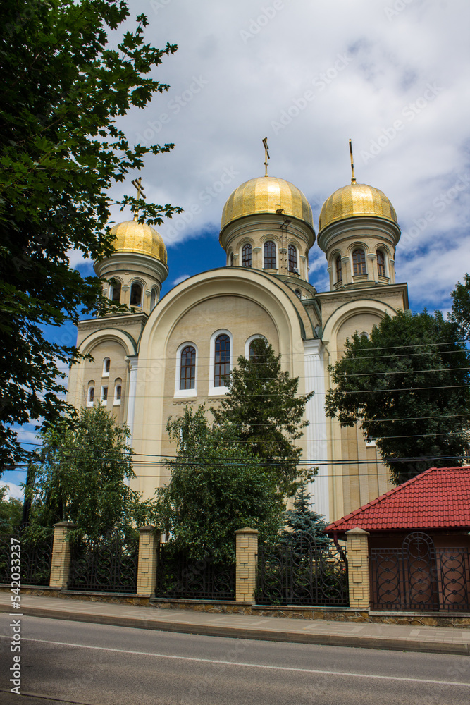 Kislovodsk, Stavropol Territory, Russia - July, 25, 2022: St. Nicholas Cathedral with golden domes among green trees on a summer day