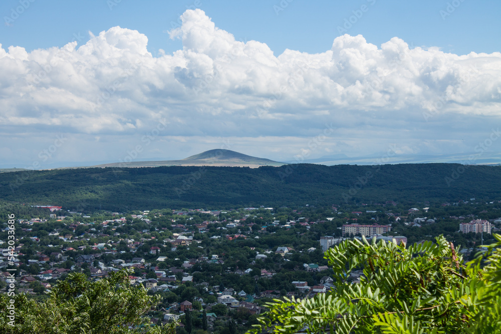 Panoramic view of Pyatigorsk in the Stavropol Territory with tasks among green trees and a mountain against the background of a dramatic cloudy sky on a summer day