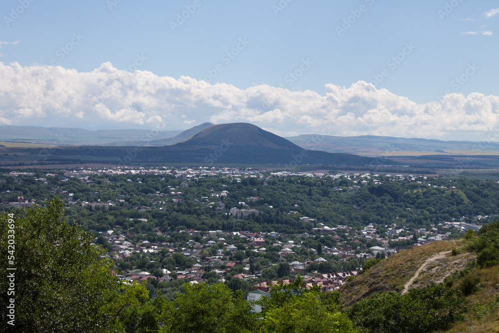 Panoramic view of Pyatigorsk in the Stavropol Territory with tasks among green trees and a mountain against the background of a dramatic cloudy sky on a summer day
