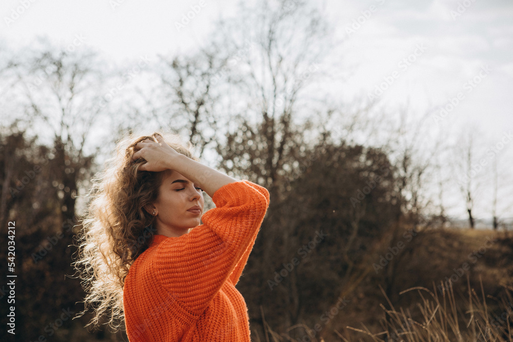 young curly girl in an orange sweater against the backdrop of autumn nature young curly girl in an orange sweater against the backdrop of autumn nature