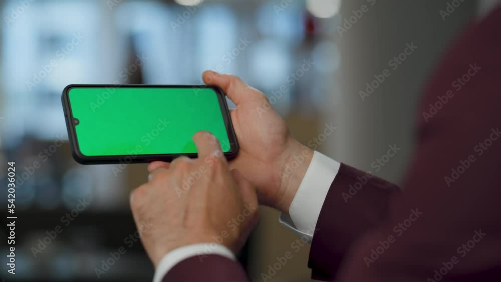 Closeup hand scrolling horizontal chromakey mobile at coworking. Man browsing Closeup hand scrolling horizontal chromakey mobile at coworking. Man browsing