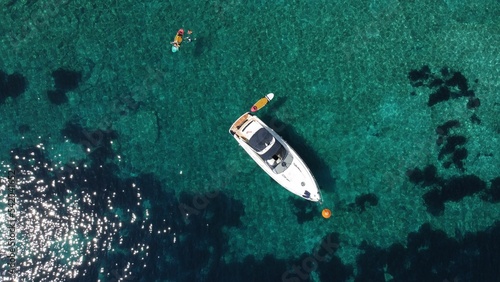 Drone shot of a boat in the tranquil sea cliff at Agia Eleni Rocky Beach in Greece