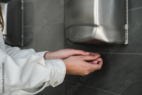 woman drying her hands with a dryer in the restroom photo