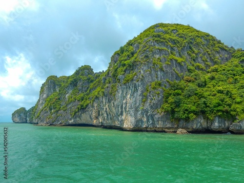Beautiful big cliff covered in trees in the sea against a cloudy sky in the Ha Long Bay Vietnam