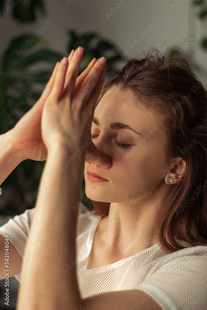 Young attractive woman practices breathing yoga at home.Relaxation and meditation.Wellness,wellbeing,mental health concept. Young attractive woman practices breathing yoga at home.Relaxation and meditation.Wellness,wellbeing,mental health concept.