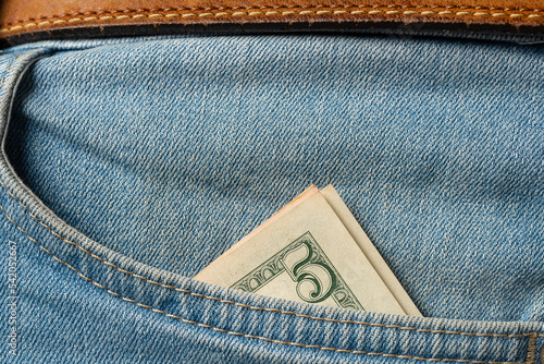 Five dollar bill in the pocket of the jeans, closeup photo