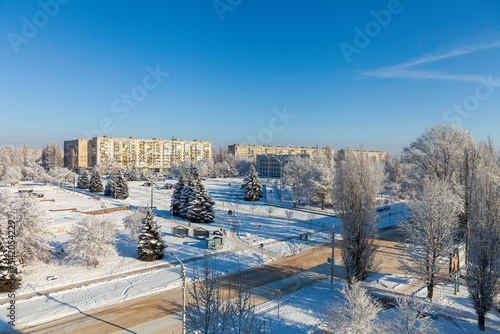 Winter frosty sunny day in the small city. Fir trees in the snow and a playground on the city square. The inscription in cyrilic means I love Rubizhne. Rubizhne city, Luhans`k reg. Ukraine