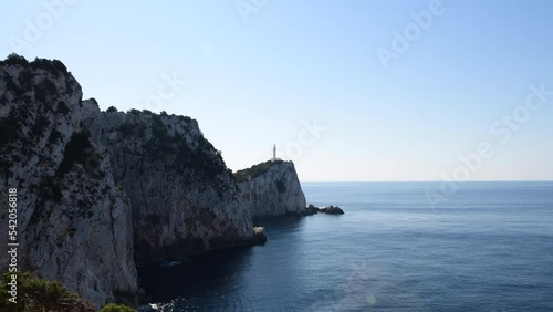 A zoom in shot of a lighthouse built on a cliff top at the cape of an island. photo