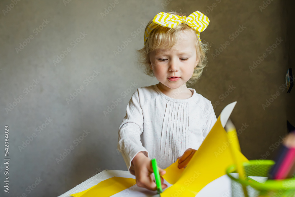 kid cutting paper and making collages. girl cuts out ornaments from colorful paper for crafting.