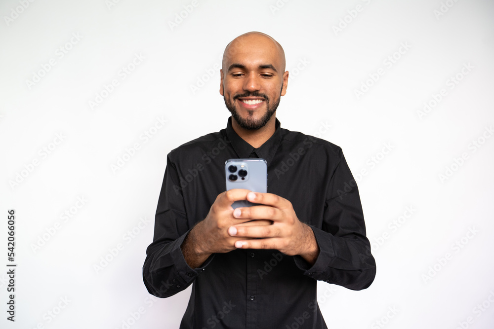 Portrait of happy young man using mobile phone. Bearded businessman wearing black shirt watching video or playing on smartphone against white background. Mobile technology concept Portrait of happy young man using mobile phone. Bearded businessman wearing black shirt watching video or playing on smartphone against white background. Mobile technology concept