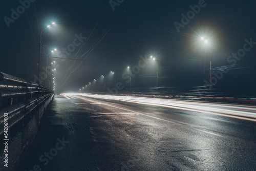 Foggy misty night road at night city illuminated by street lights