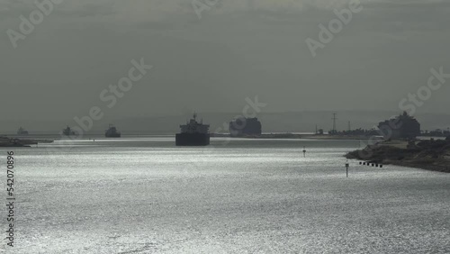 Suez canal. Ships sail in silhouette one after the other. Ships sail in caravan along river