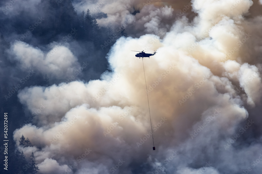 Wildfire Service Helicopter flying over BC Forest Fire and Smoke on the mountain near Hope during a hot sunny summer day. British Columbia, Canada. Natural Disaster Wildfire Service Helicopter flying over BC Forest Fire and Smoke on the mountain near Hope during a hot sunny summer day. British Columbia, Canada. Natural Disaster