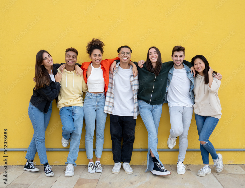 Obraz premium Group of young multiethnic friends laughing looking at camera on a yellow wall. Friendship and diversity concept