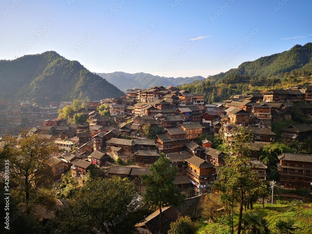 Buildings of Xijiang Qianhu Miao village surrounded by mountains full of forests