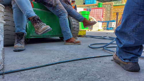 Girls wearing boots at a construction site.