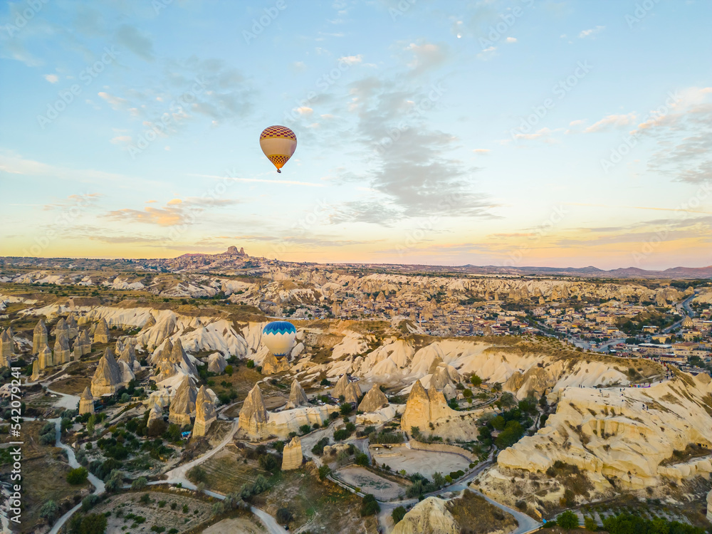 Breathtaking drone view of hot air balloons flying over the Red Valley in Cappadocia in Turkey at dawn. Fairy chimneys or hoodoos during the sunrise. High quality photo