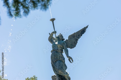Angel blowing a trumpet figure in a water fountain in a park