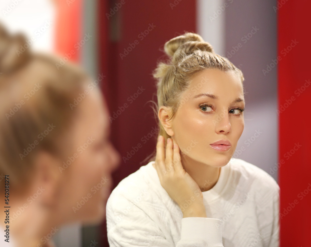 woman looking in the mirror in the bathroom and taking care of her skin.Applying the cream..Magic anti-aging cream. woman looking in the mirror in the bathroom and taking care of her skin.Applying the cream..Magic anti-aging cream.