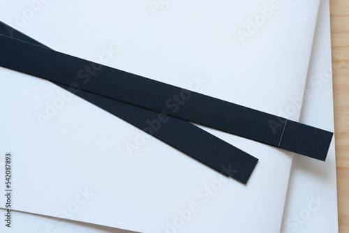 two black paper stripes on bristol board on wood