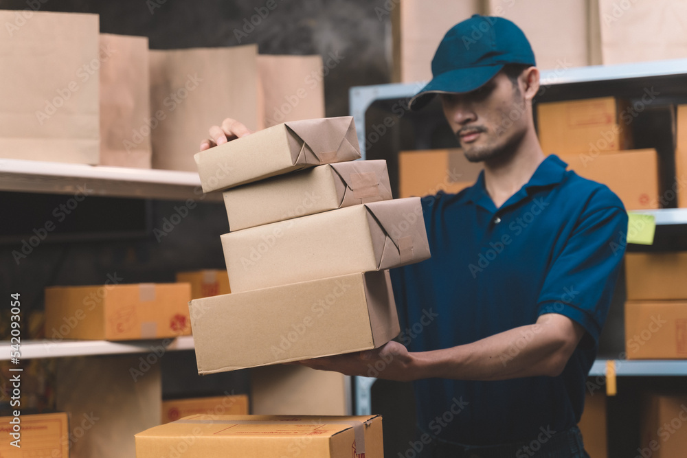 deliveryman sorting customer package prepare for transport and shipping to customer home. man doing work at his small shipping new business and new transportation delivery. deliveryman sorting customer package prepare for transport and shipping to customer home. man doing work at his small shipping new business and new transportation delivery.