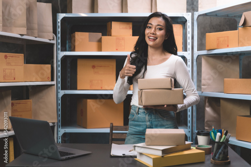 young beautiful woman smiling and happy with thumbs up handle the parcel. Young women packing a parcel order for shipping service to online customer.
